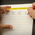 A person is writing the letters of the alphabet on a piece of paper.
