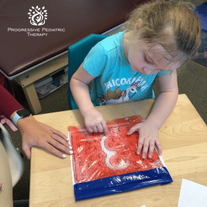 A little girl is playing with a bag that says progressive pediatric therapy