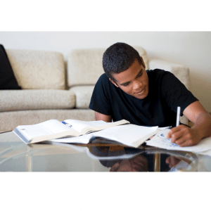 A man in a black shirt is sitting at a table writing in a notebook
