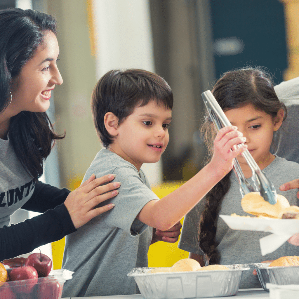 A woman and two children are sitting at a table eating food.