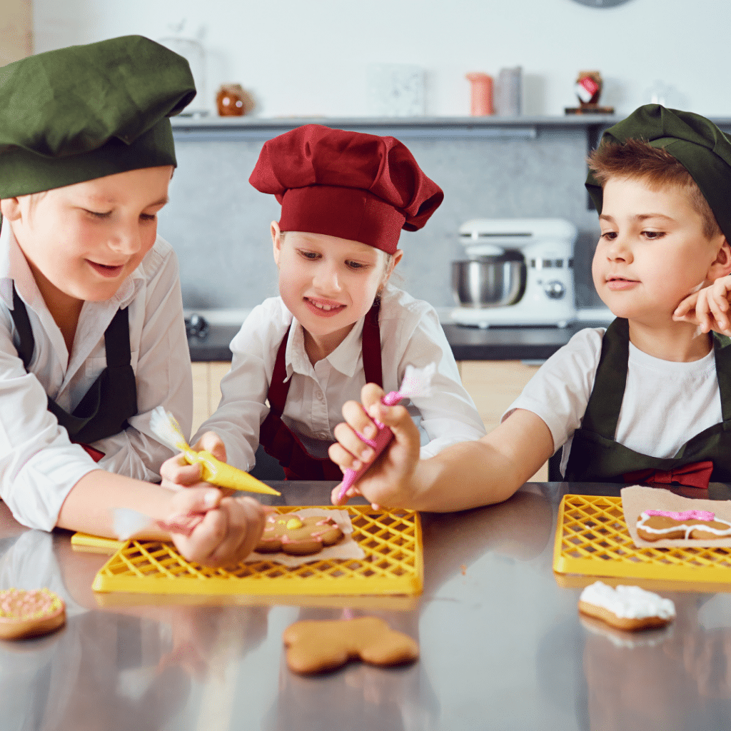 Three young boys are sitting at a table decorating cookies.