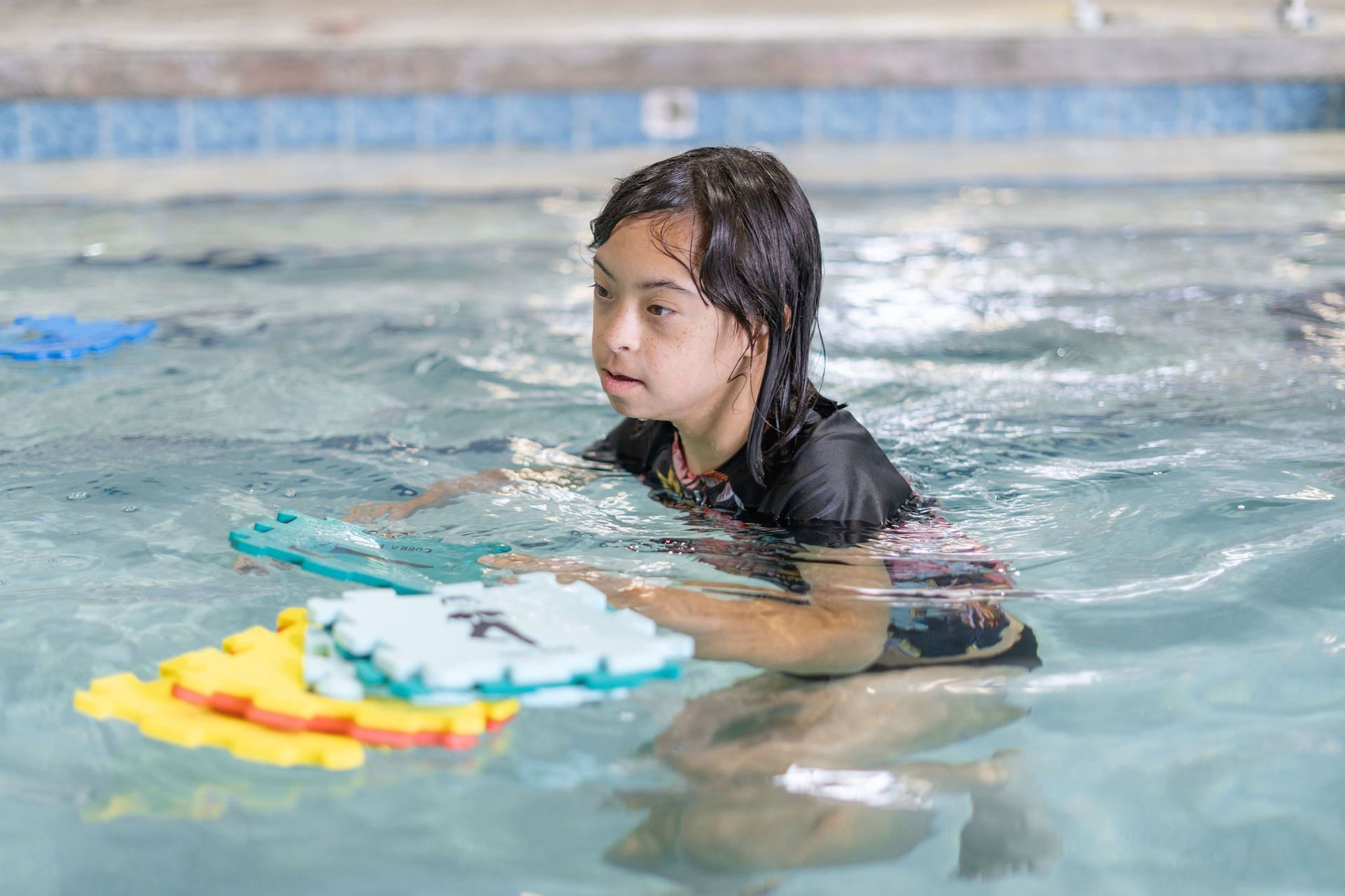 A young girl is swimming in a swimming pool.