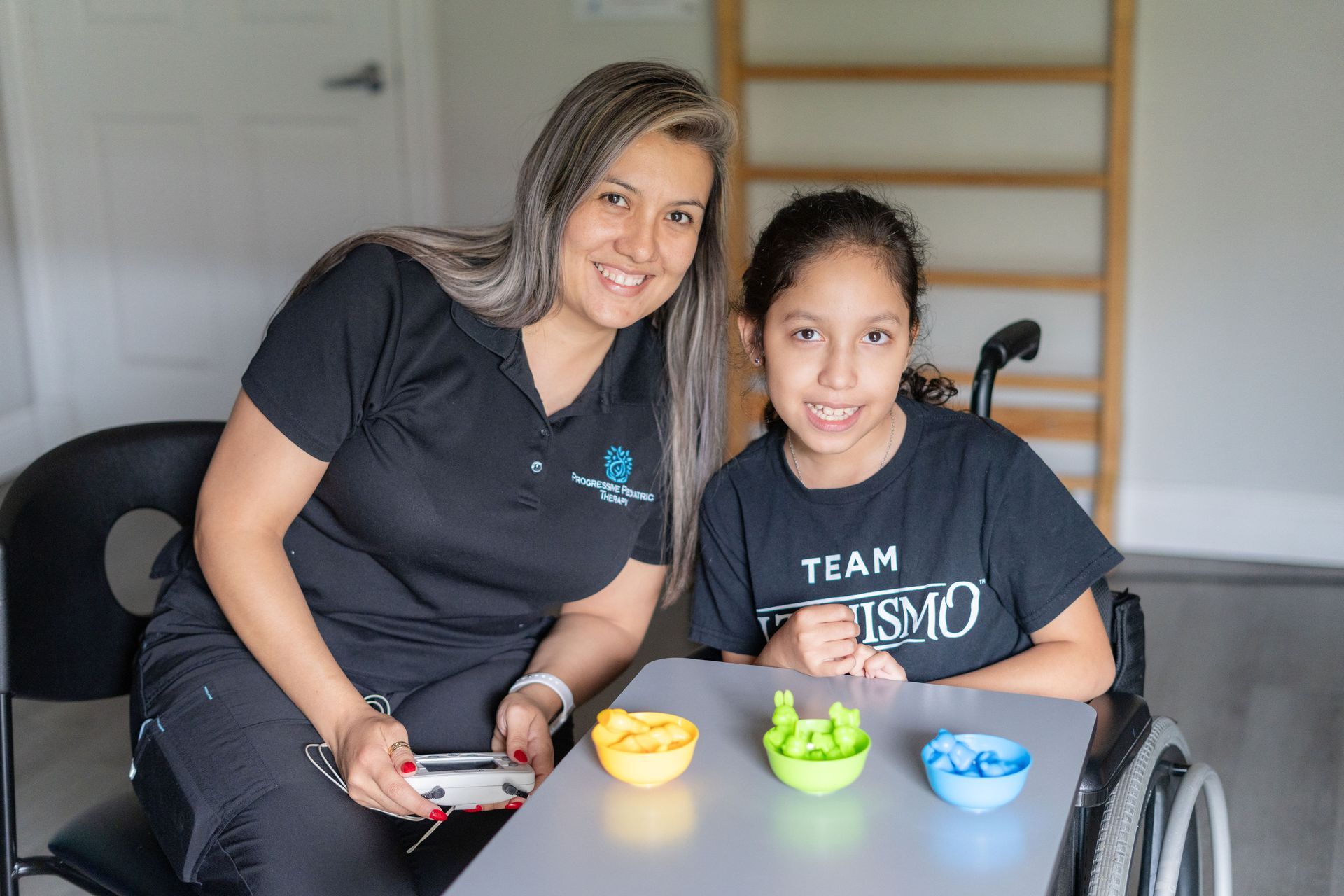A woman is sitting next to a girl in a wheelchair at a table.