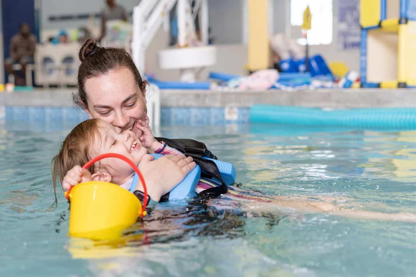 A woman is teaching a child how to swim in a swimming pool.