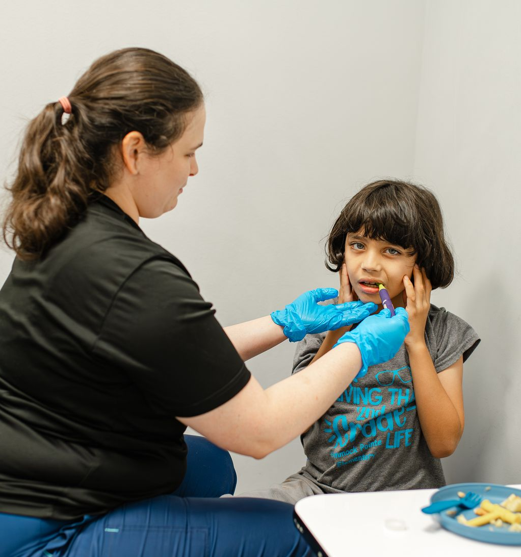 A woman and child are sitting at a table with a rainbow cake on a plate