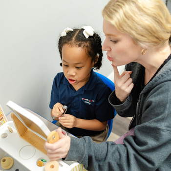 A little boy is sitting in a chair talking to a woman who is holding a clipboard