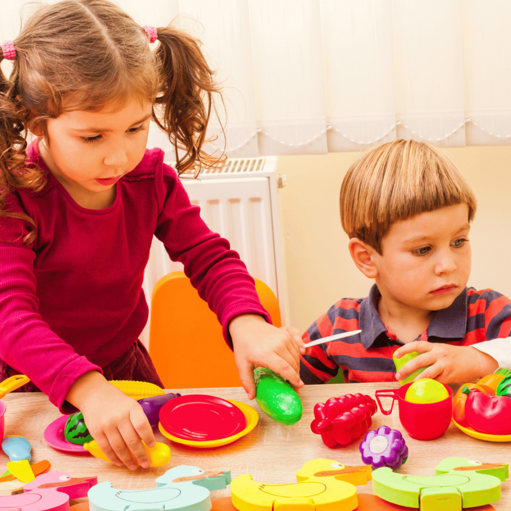 A boy and a girl are playing with toys on a table.