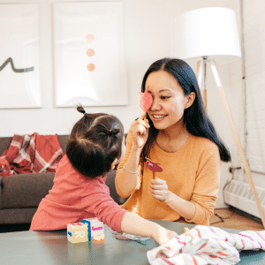 A woman and a little girl are sitting at a table playing with blocks.