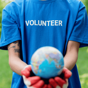 A person wearing a blue volunteer shirt is holding a globe in their hands