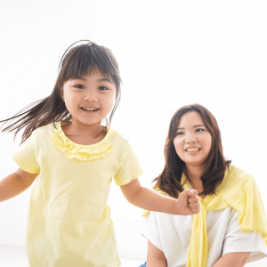 A little girl is holding the hand of a woman who is sitting next to her.