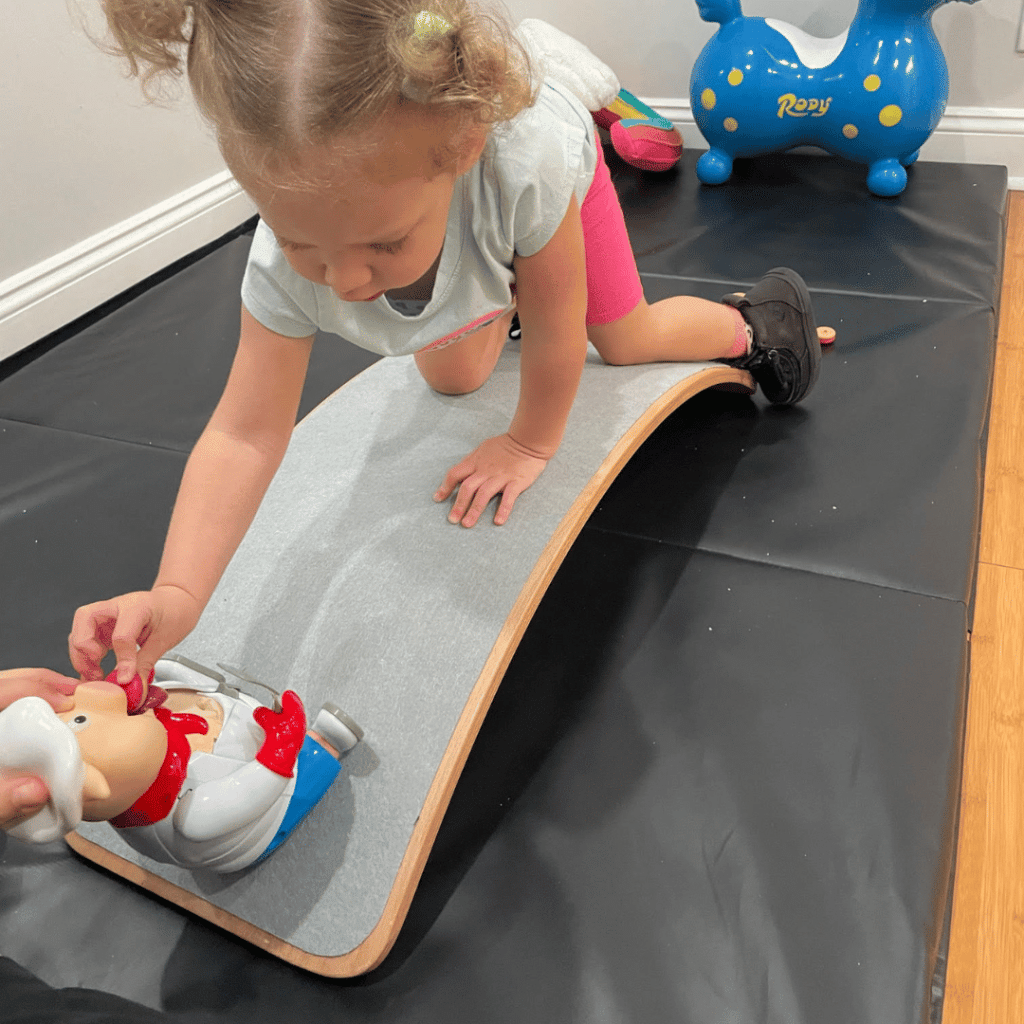 A little girl is playing with a toy chef on a balance board