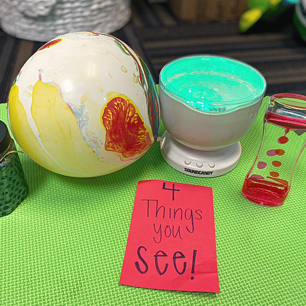 A table with a beach ball , a bowl of liquid , and a sign that says `` 4 things you see ! ''