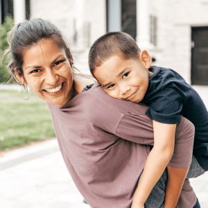 A woman is carrying a young boy on her back.