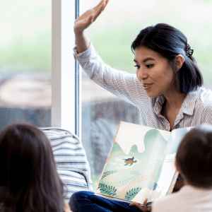 A woman is reading a book to a group of children.