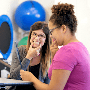 Two women are sitting at a table talking to each other.