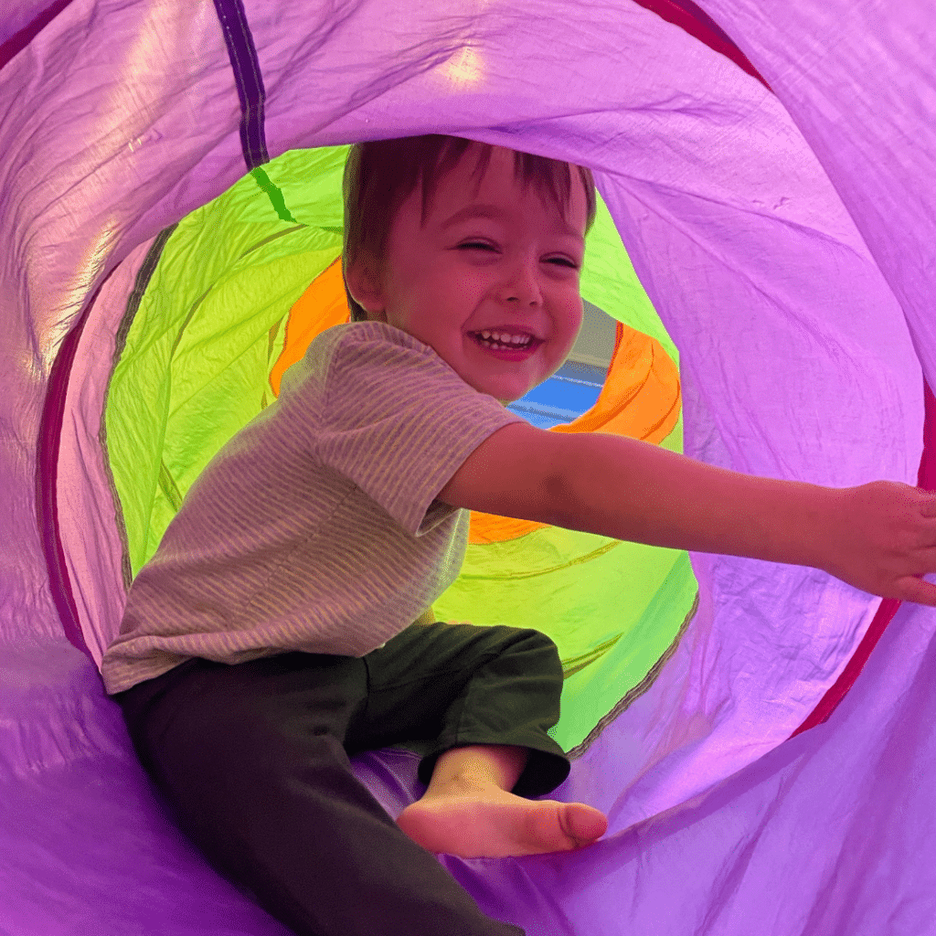 A young boy is playing in a colorful tunnel