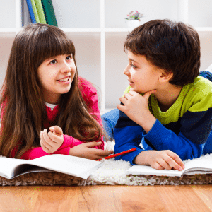 A boy and a girl are laying on the floor looking at each other.