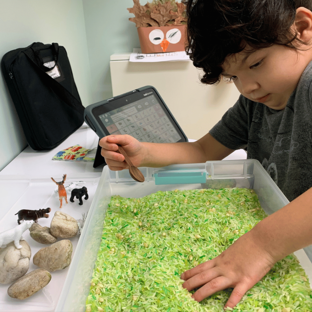 A young boy is playing with green rice and a tablet