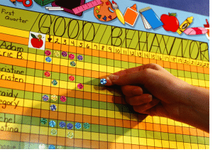 A child 's hand is pointing at a good behavior chart