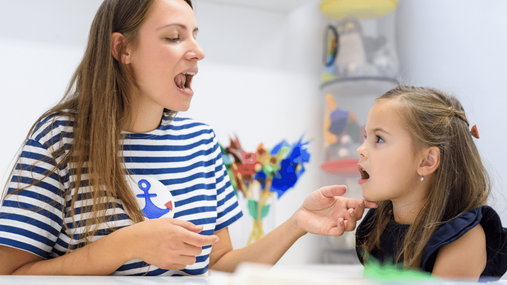 A woman is talking to a little girl who is sitting at a table.