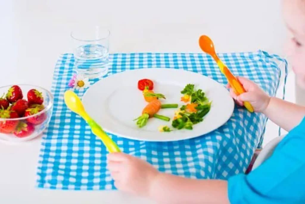A child is sitting at a table with a plate of food on it.