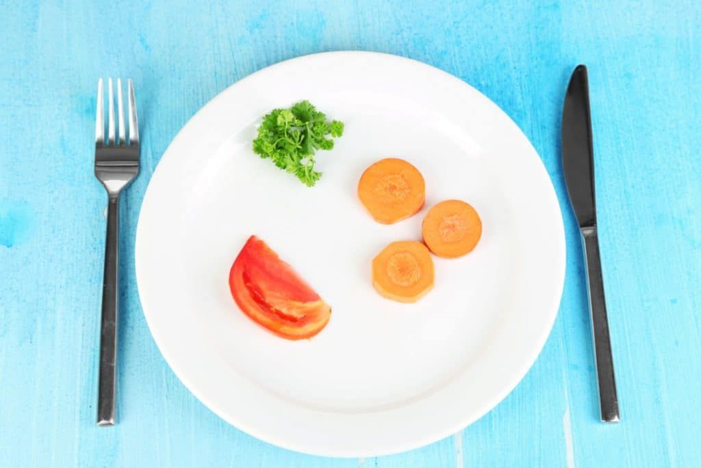 A white plate with carrots , tomatoes , and parsley on it.