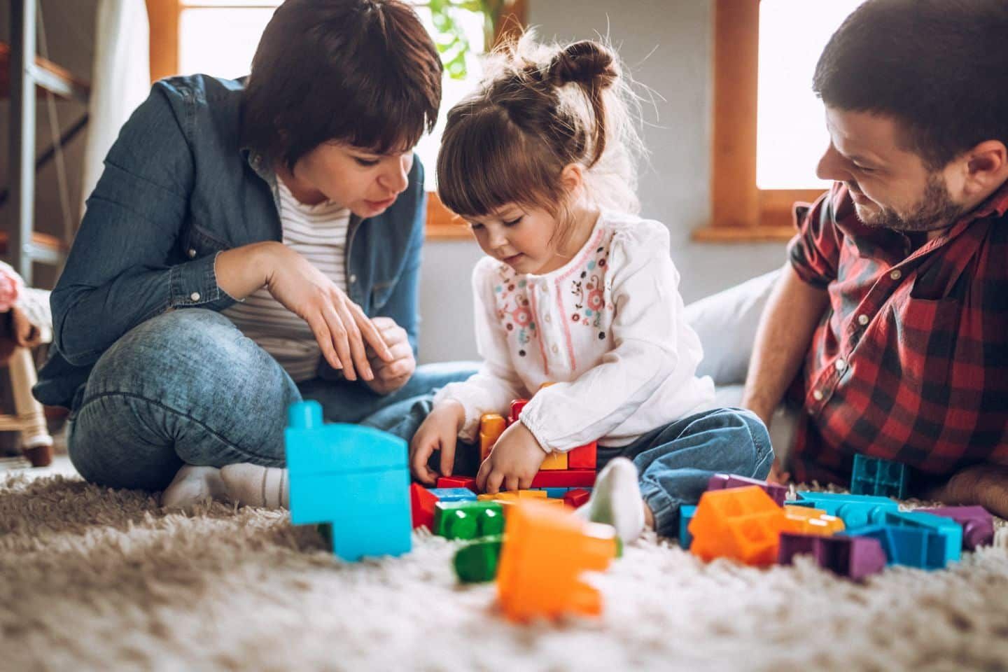 A family is sitting on the floor playing with toys.