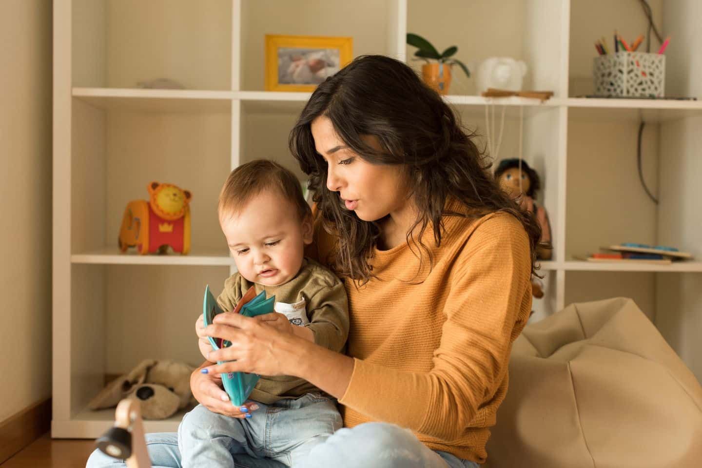 A woman is sitting on a bean bag chair holding a baby.