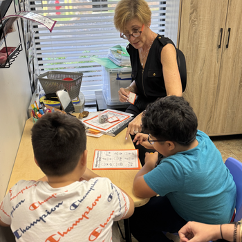 A woman and child are sitting at a table with a rainbow cake on a plate