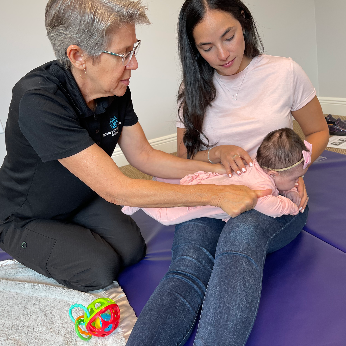 A little girl is sitting on a man 's lap holding a green object