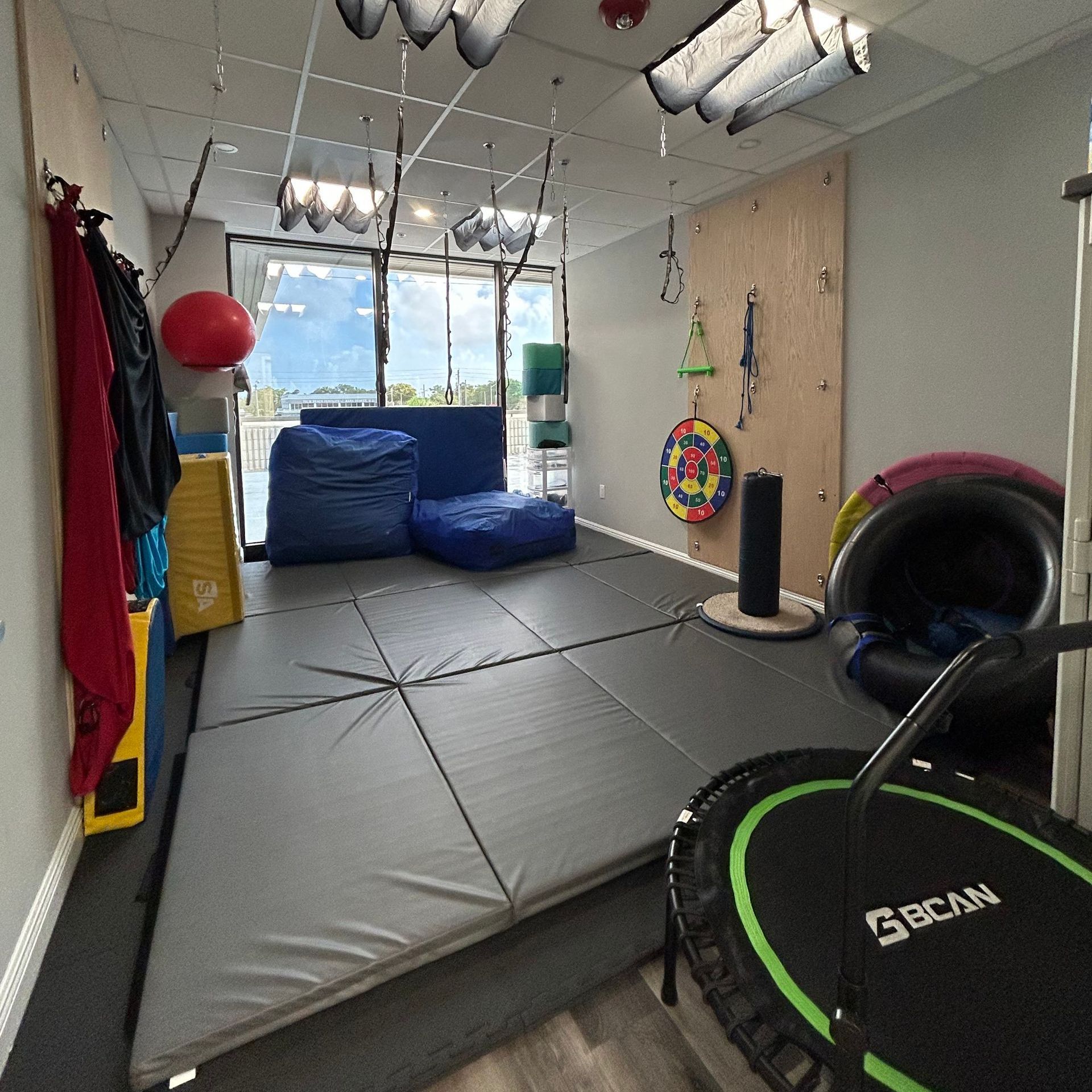 A room with a lot of mats and toys on the floor.