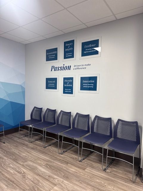 Waiting area with blue chairs and wall art that says 