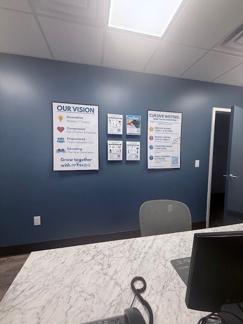 Blue office wall with posters, a white countertop, and a gray office chair.
