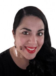 A woman wearing red lipstick and earrings smiles for the camera