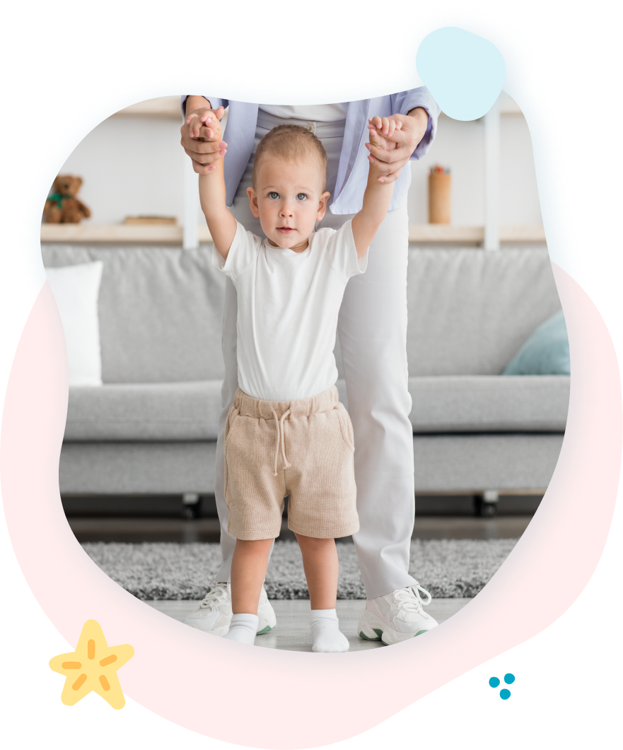 A woman is holding a baby 's hands in a living room.