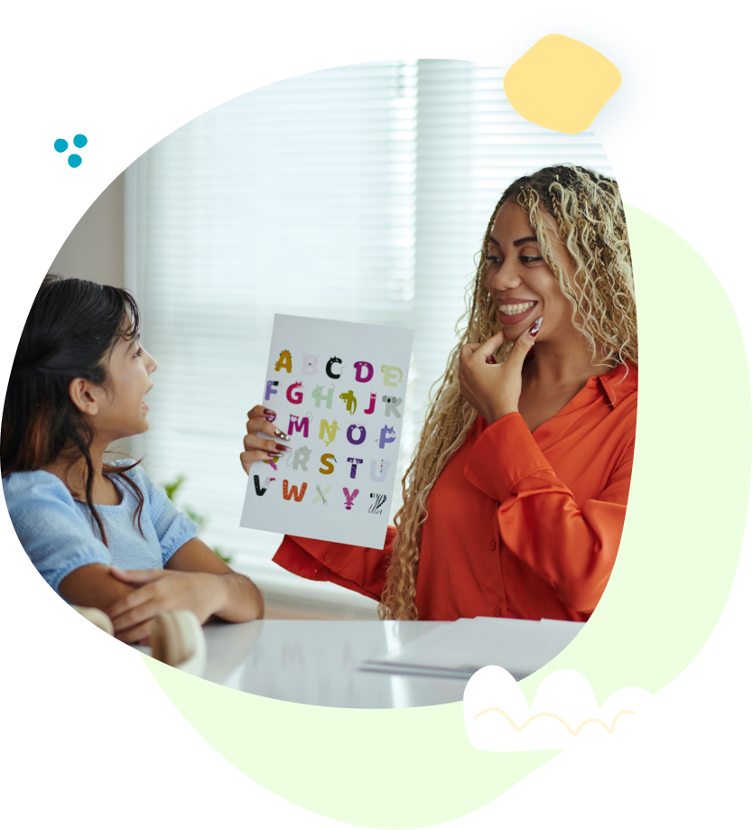 A woman is holding a piece of paper with the alphabet on it.