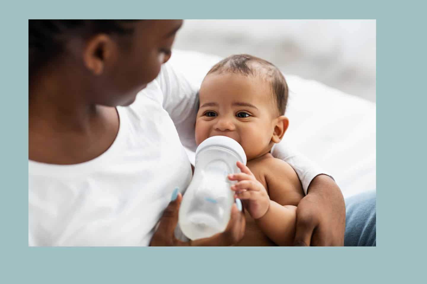 A woman is holding a baby who is drinking from a bottle.