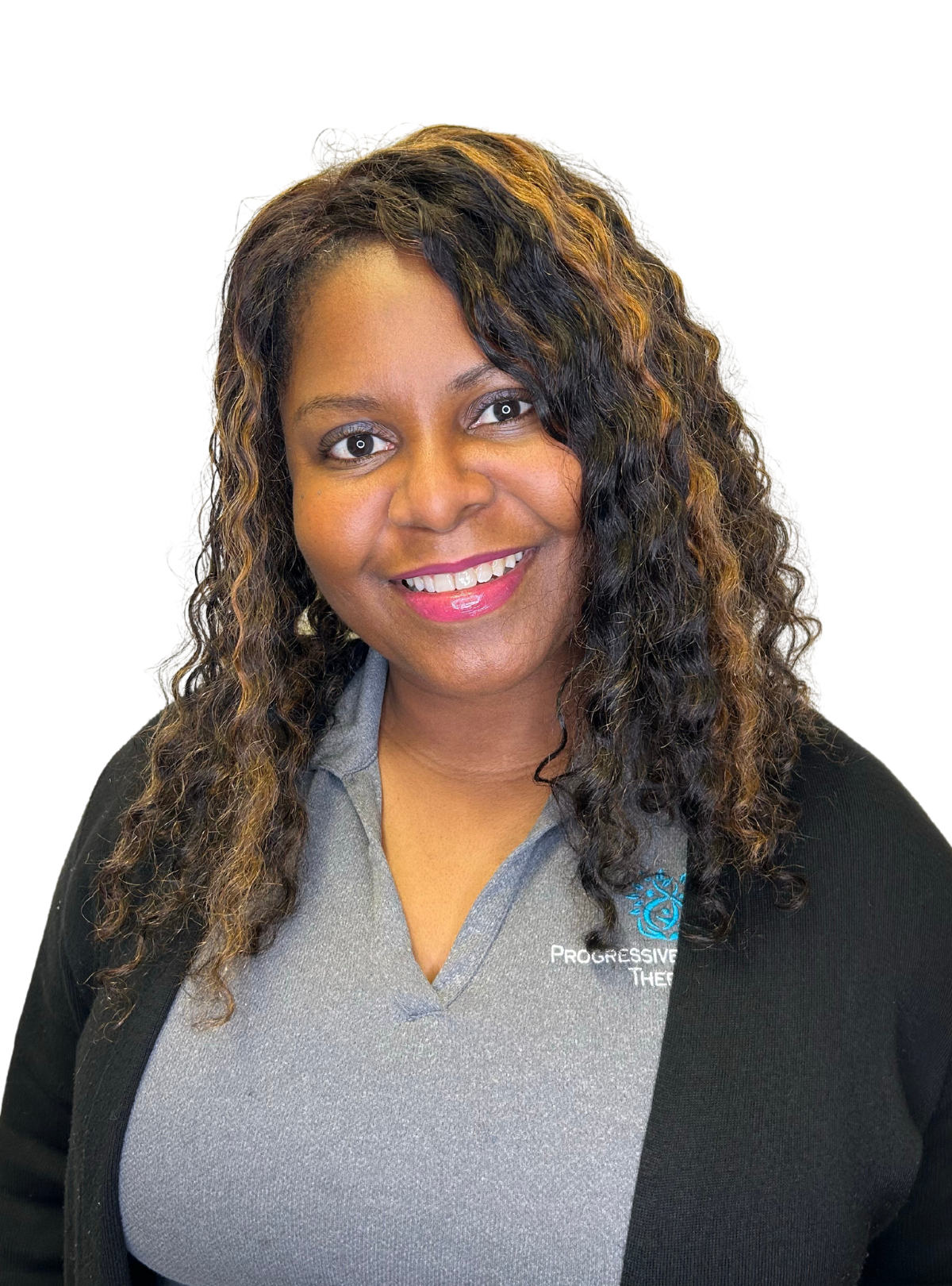 A woman with curly hair is smiling and wearing a gray shirt and a black cardigan.