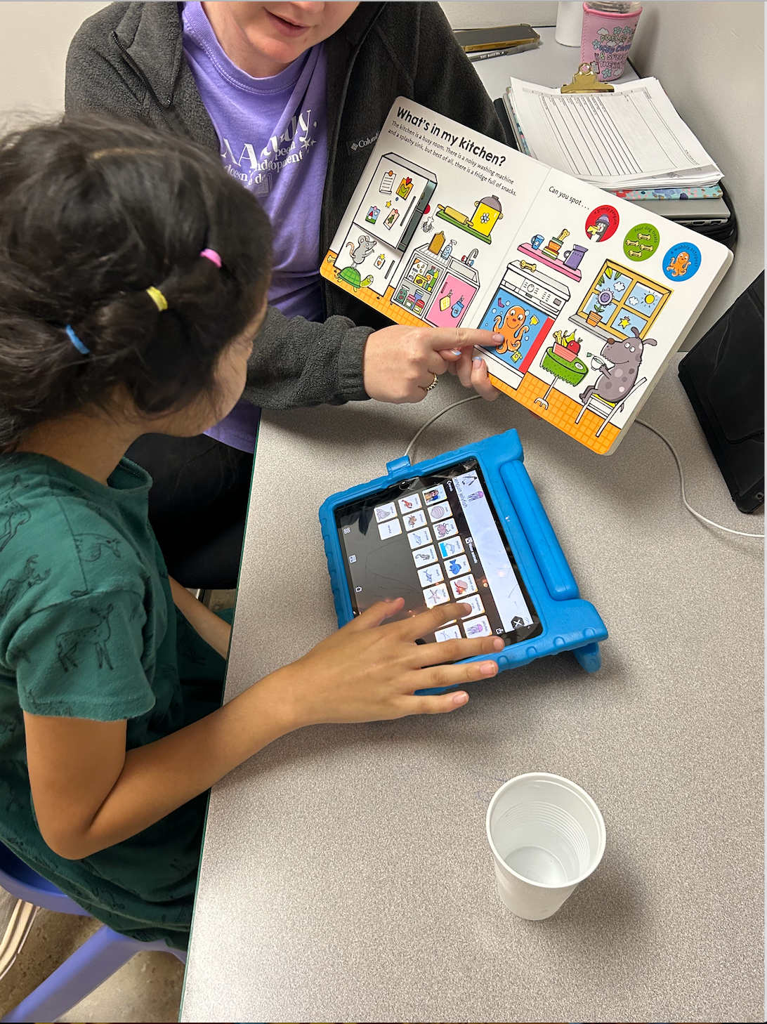 A woman is teaching a young girl how to use a tablet computer.