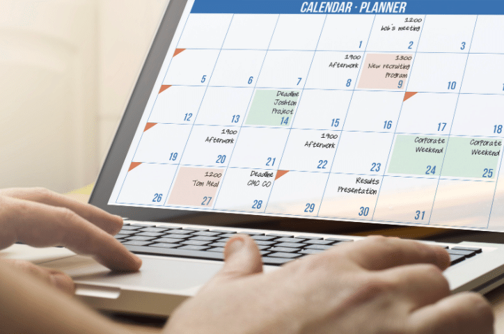 A person is typing on a laptop with a calendar on the screen.