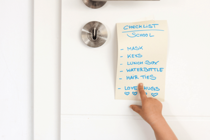 A person is pointing at a checklist on a white board.