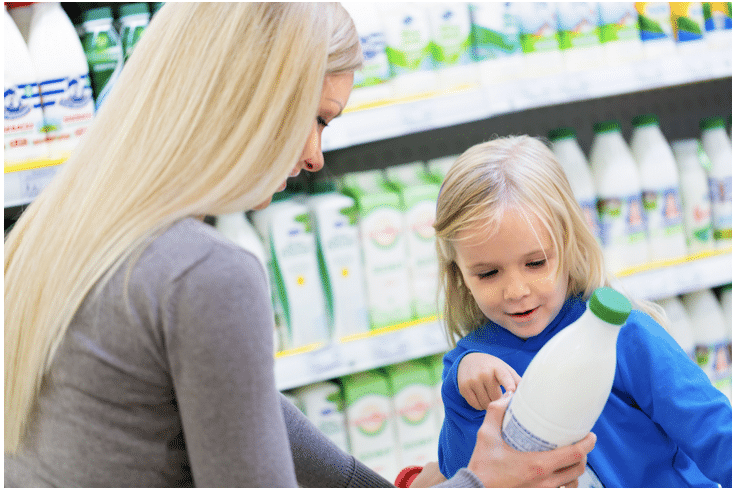 A woman and child are looking at a bottle of milk