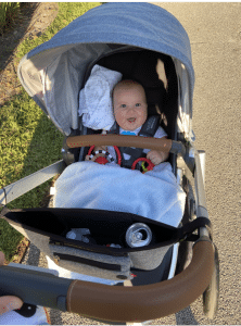 A baby is sitting in a stroller on a sidewalk.