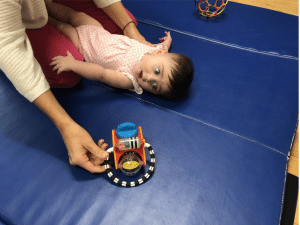 A woman is playing with a baby on a blue mat