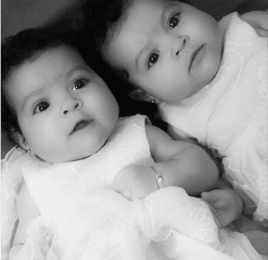 A black and white photo of two babies laying next to each other