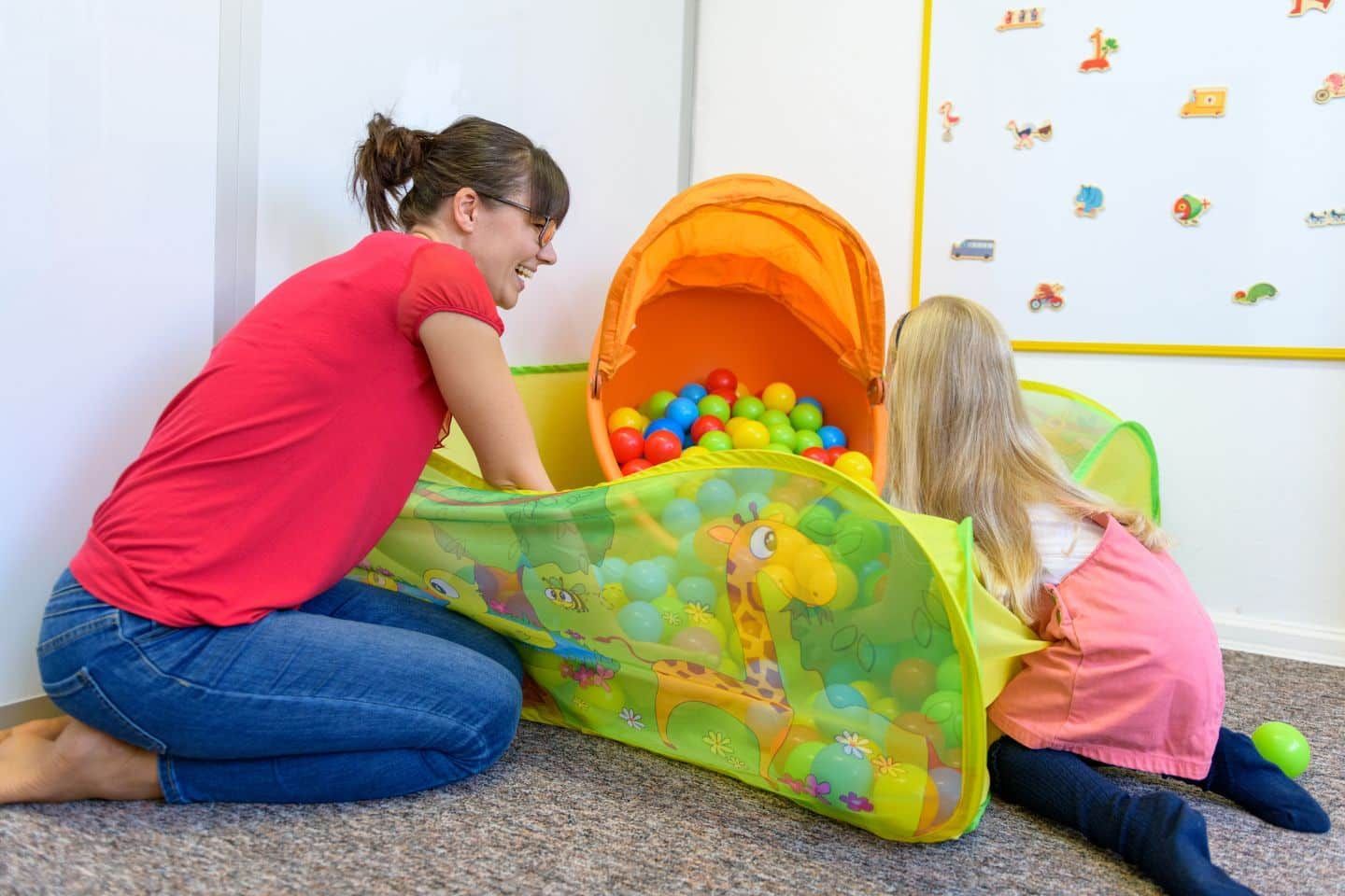 A woman and a child are playing in a ball pit.