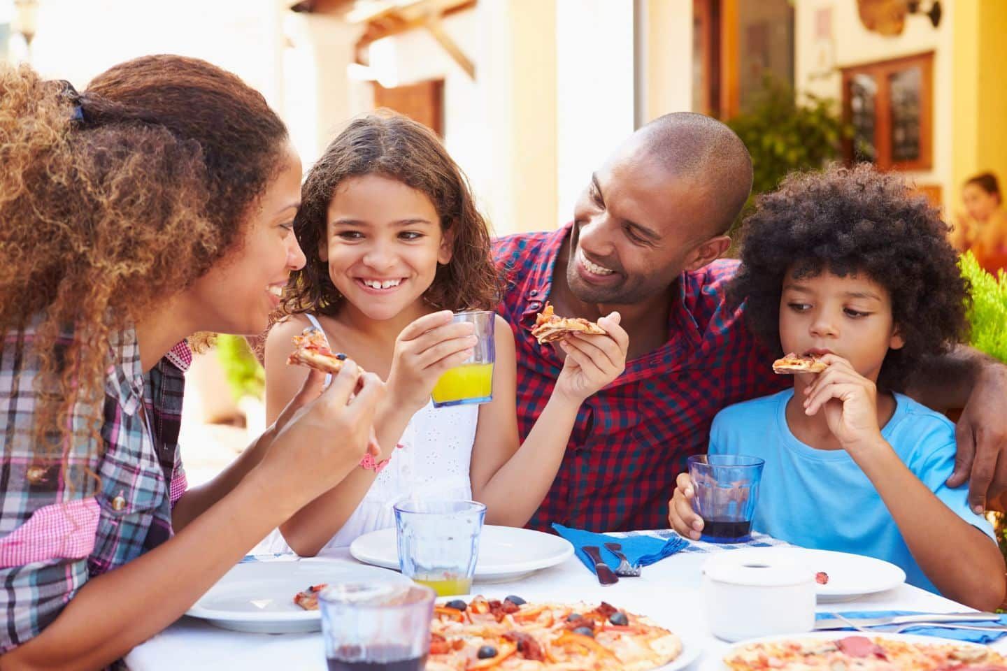 A family is sitting at a table eating pizza.