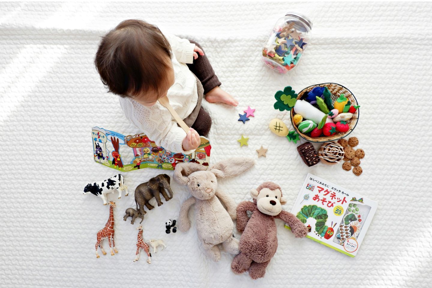 A baby is sitting on the floor surrounded by toys and a book.