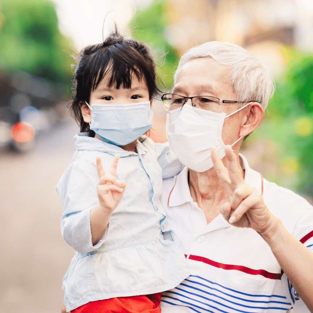 A man is holding a little girl wearing a face mask.