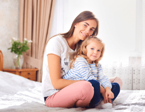 A woman and a little girl are sitting on a bed.